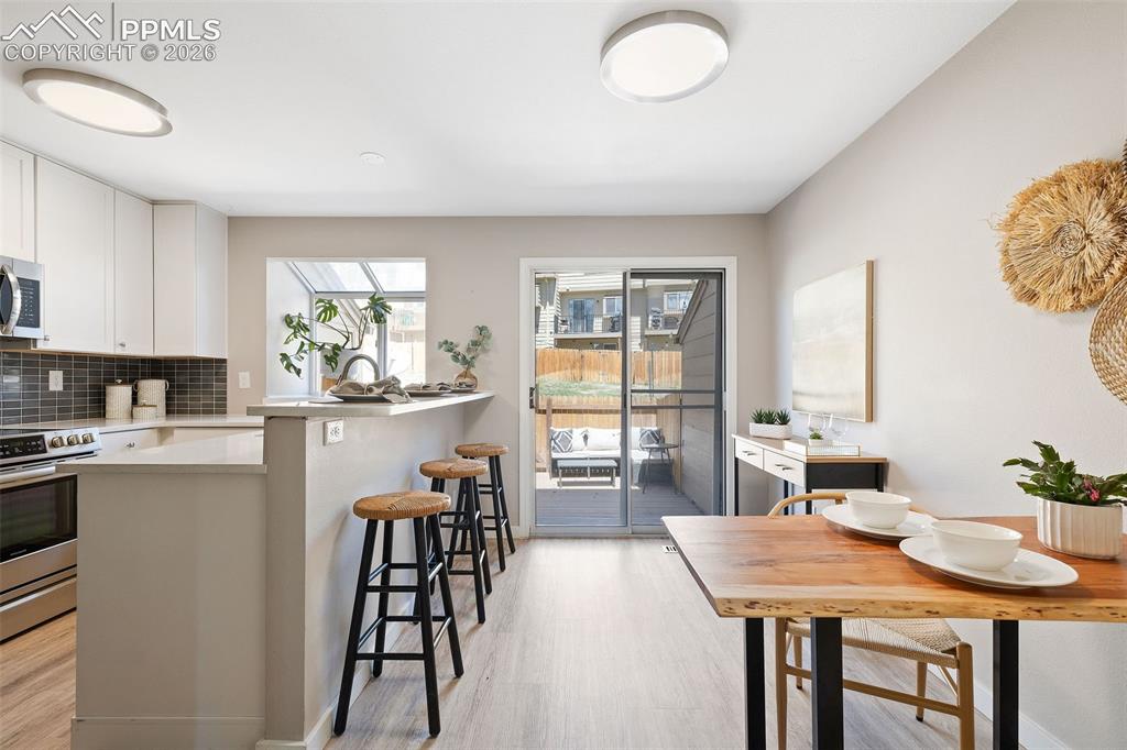 Image 6 of 26: Open-concept kitchen and dining area featuring light wood-finish flooring, 