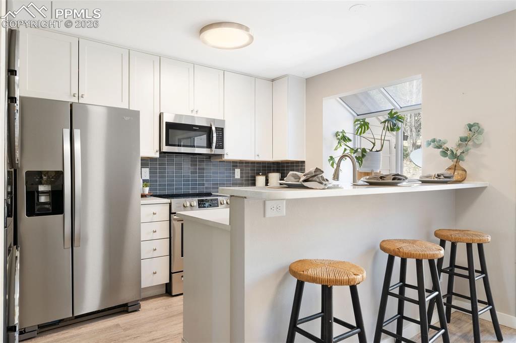 Image 7 of 26: Contemporary kitchen featuring white cabinetry, stainless steel appliances,