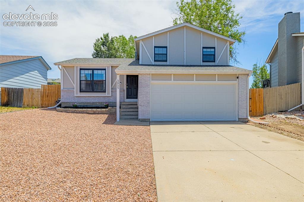 Image 1 of 29: Split-level residence featuring a two-car garage, light gray siding with wh