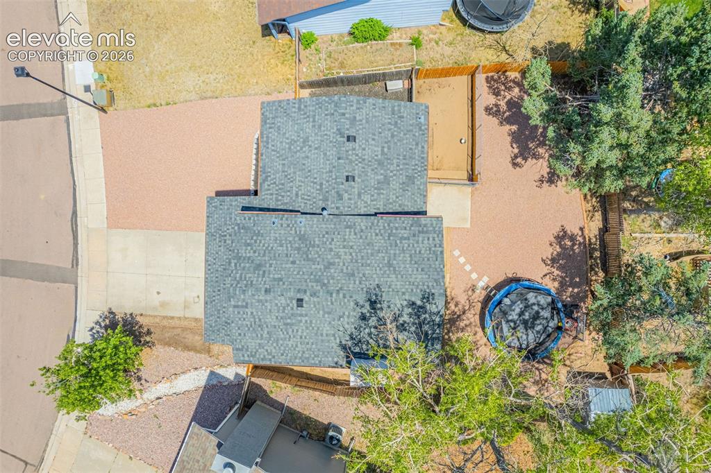 Image 25 of 29: Property featuring an asphalt shingle roof, concrete driveway, and gravel l