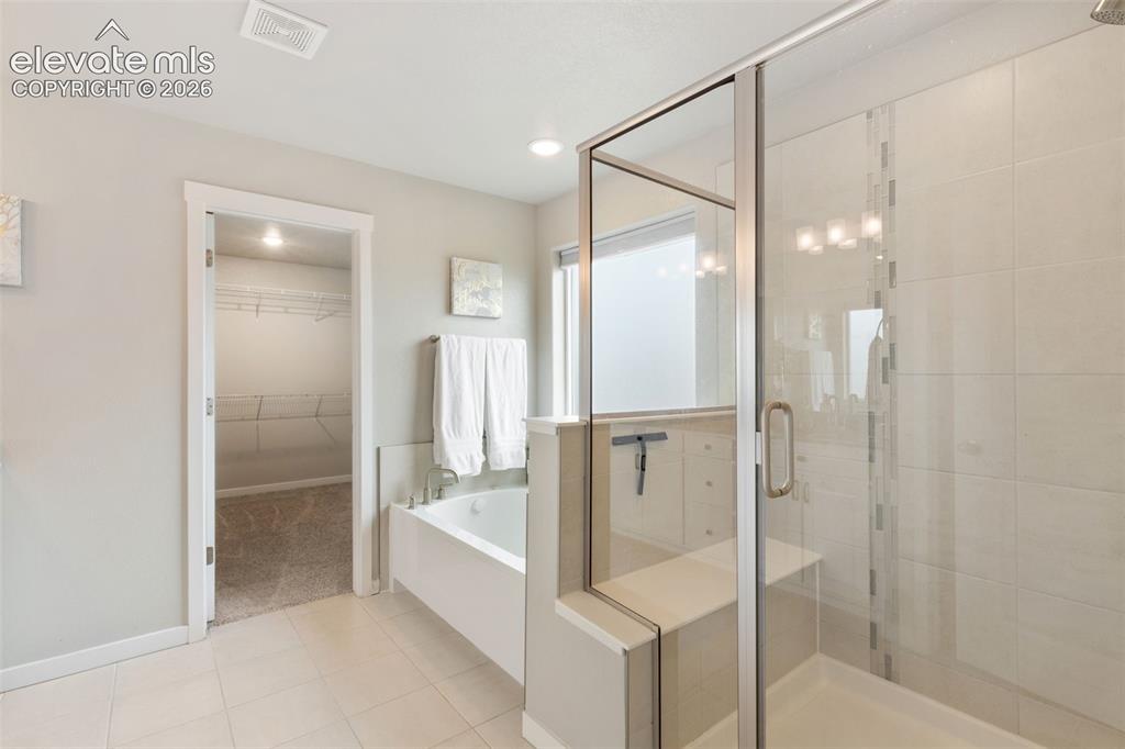 Image 20 of 27: Bathroom featuring a glass-enclosed shower with an integrated bench, tile f