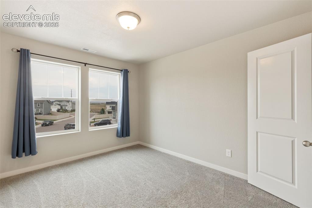 Image 22 of 27: Bright room featuring two large windows with white blinds, grey carpet floo