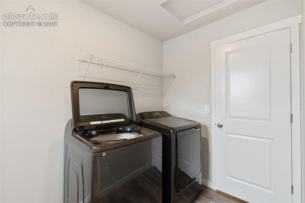 Image 25 of 27: Dedicated laundry area featuring wood-finish flooring, a white interior doo