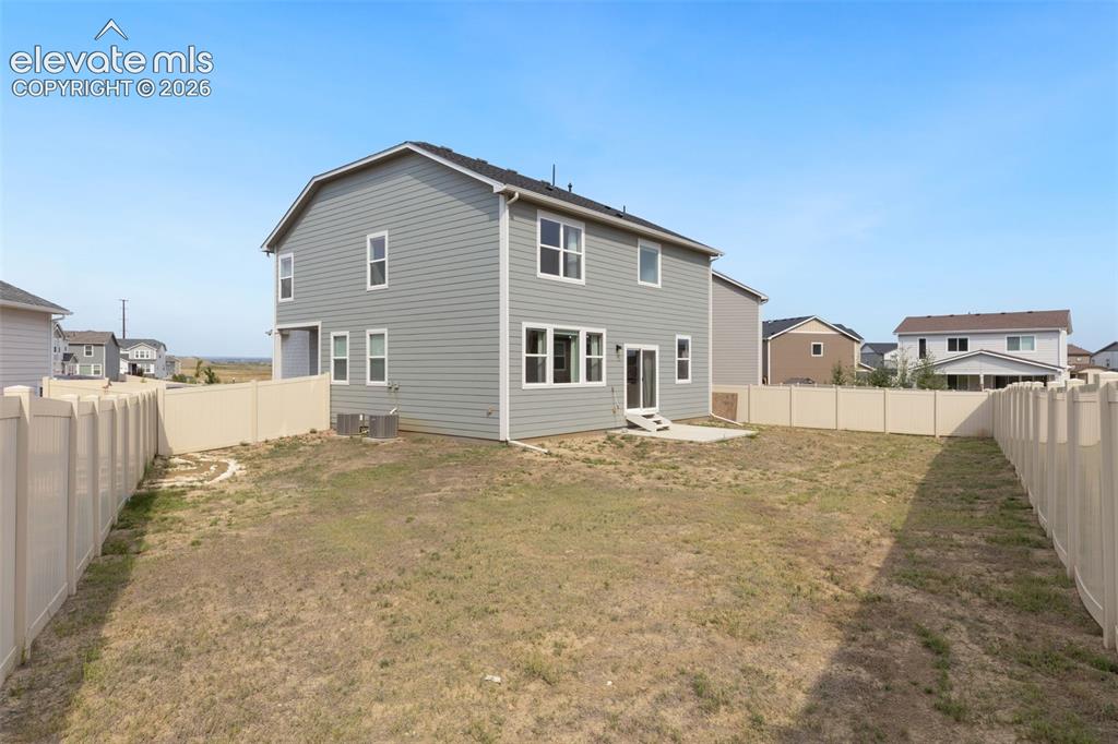 Image 26 of 27: Expansive backyard featuring a new vinyl fence, concrete patio, and a two-s