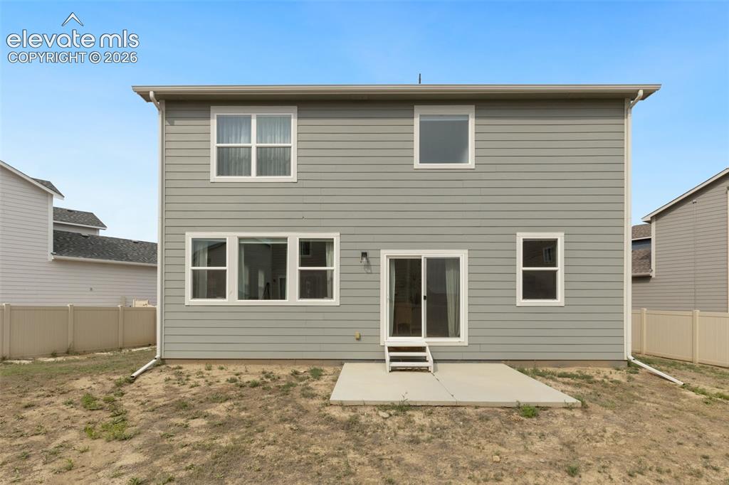 Image 27 of 27: Rear exterior featuring light gray siding with white trim, a concrete patio
