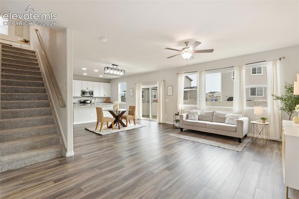 Image 4 of 27: Open-concept living area featuring wood-finish flooring, a carpeted stairca