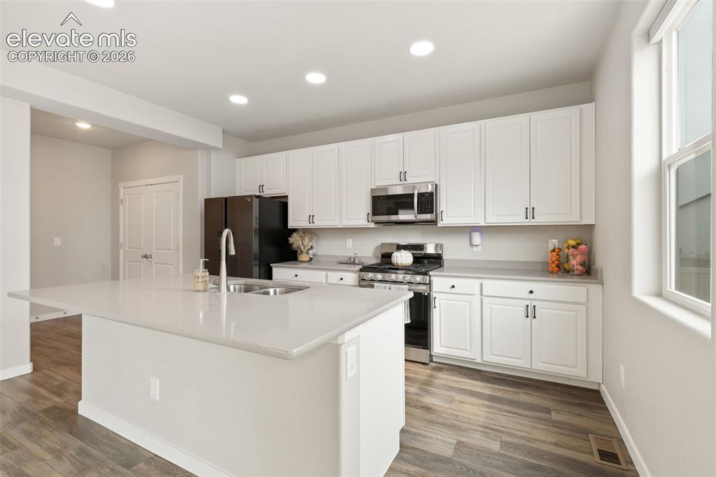 Image 7 of 27: Modern kitchen featuring a large island with an undermount sink, light-tone