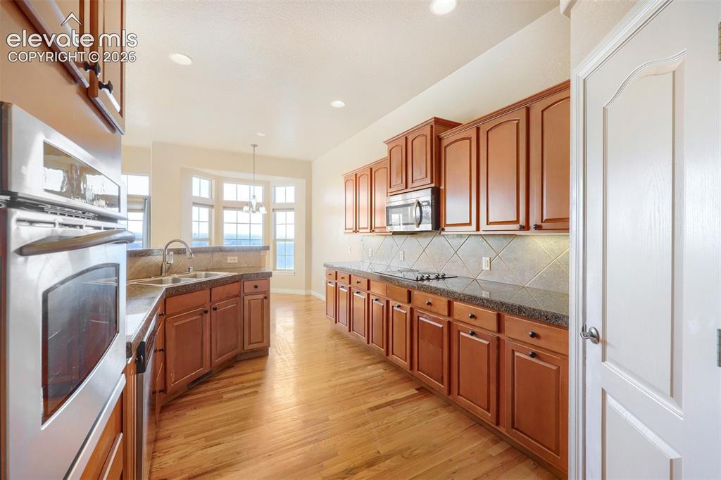 Image 10 of 32: Expansive cooks delight kitchen featuring hardwood flooring, abundant wood 