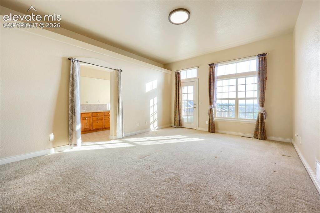 Image 13 of 32: Main level large walk out primary bedroom with walk in closet in 5-piece ba