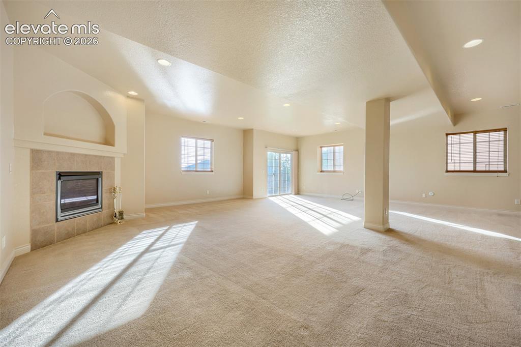 Image 21 of 32: Spacious basement family room interior with neutral carpeting, recessed lig