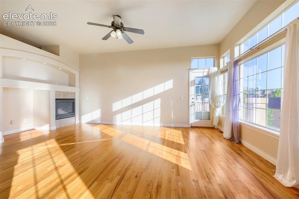 Image 6 of 32: Hardwood flooring throughout, a fireplace with a tile surround, built-in sh
