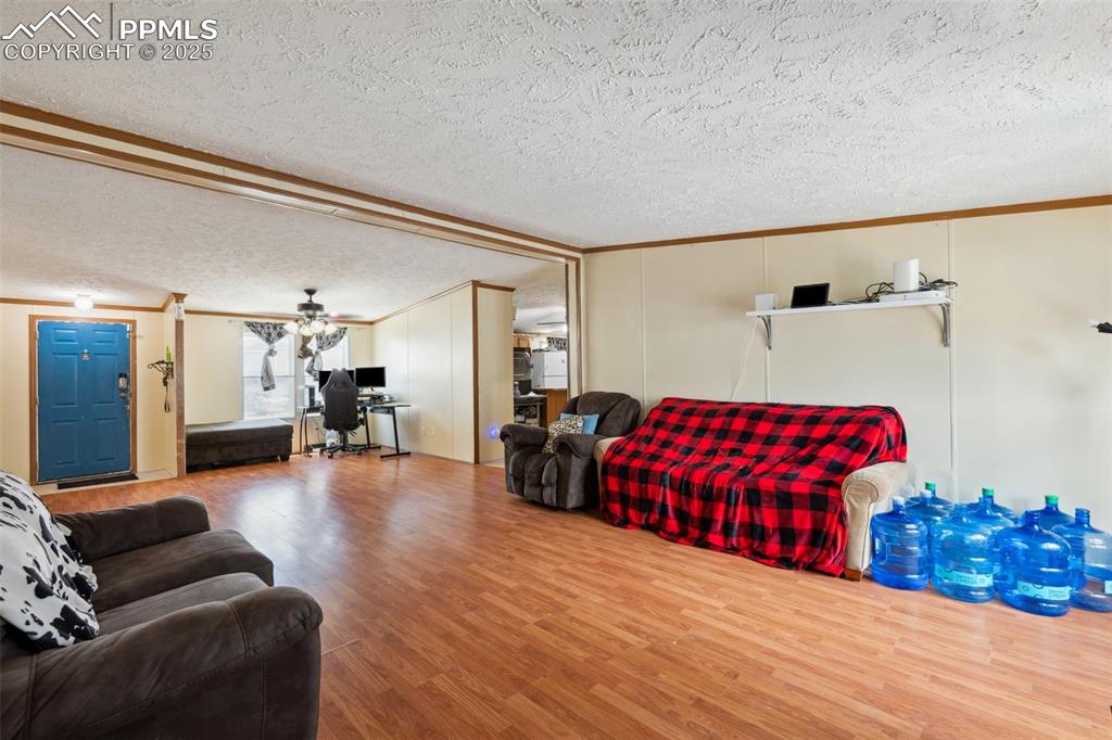 Image 18 of 34: Living room featuring crown molding, wood finished floors, a textured ceili