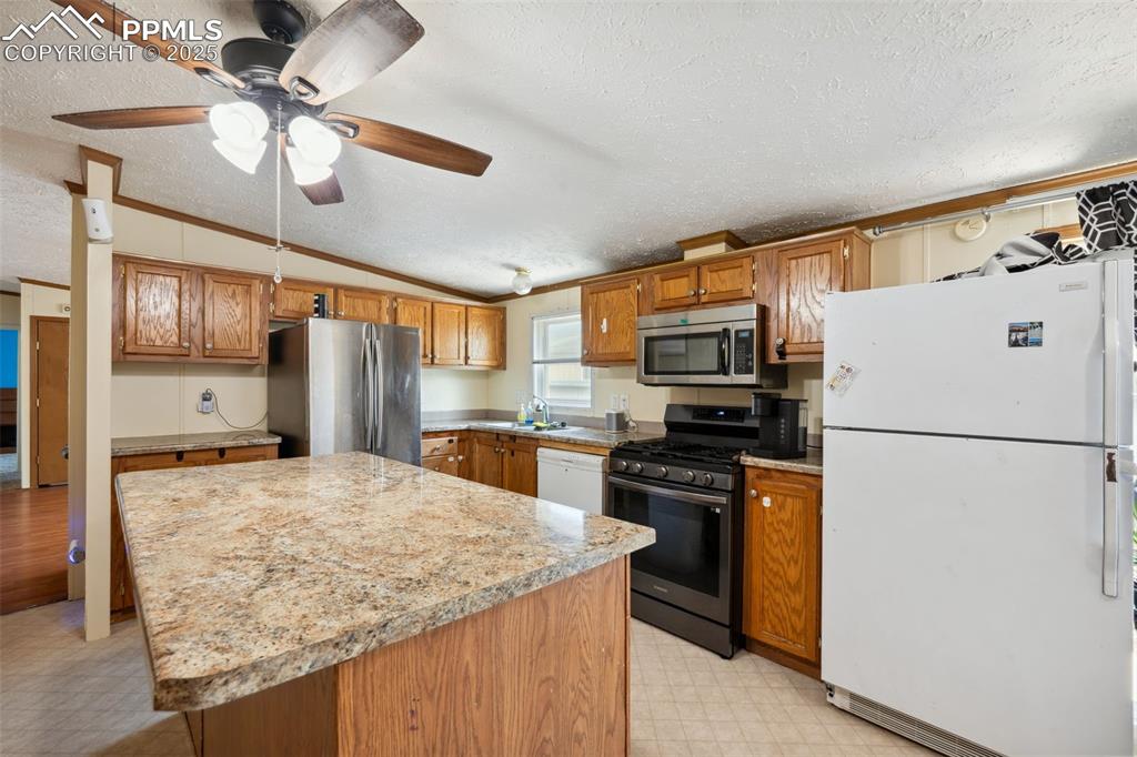 Image 21 of 34: Kitchen featuring stainless steel appliances, light flooring, a textured ce