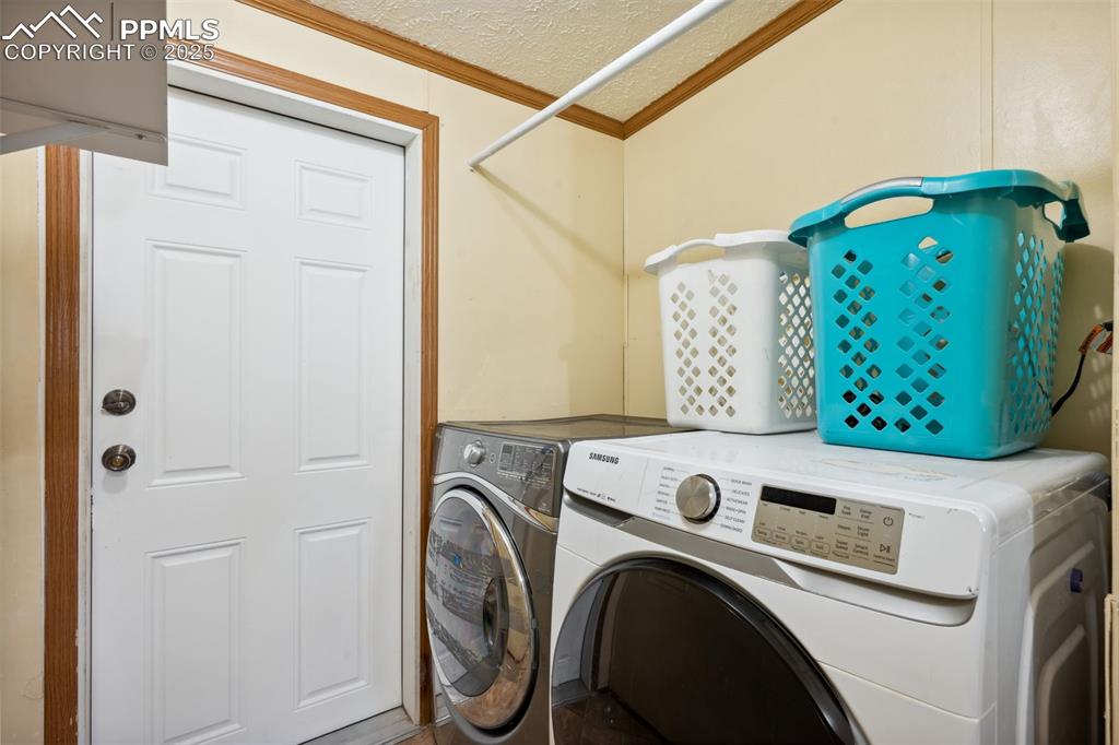 Image 22 of 34: Laundry room featuring separate washer and dryer, crown molding, and a text