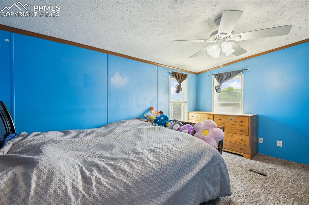 Image 23 of 34: Bedroom with a textured ceiling, carpet flooring, ornamental molding, and c