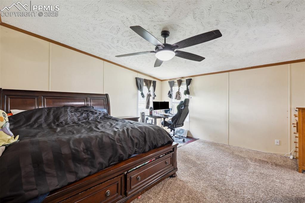 Image 25 of 34: Carpeted bedroom featuring a textured ceiling, vaulted ceiling, crown moldi