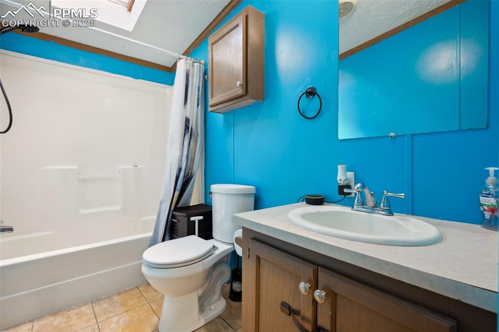 Image 31 of 34: Bathroom featuring vanity, shower / bath combo, toilet, a skylight, and til