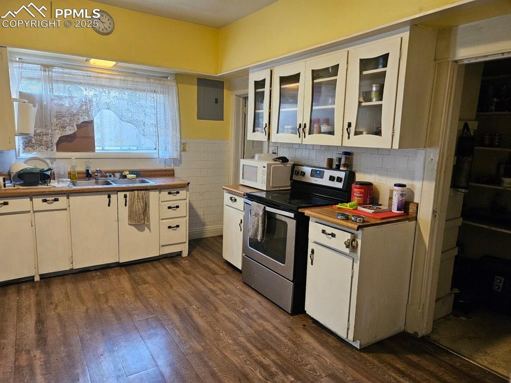 Image 12 of 14: Kitchen with electric panel, stainless steel electric stove, dark wood-type