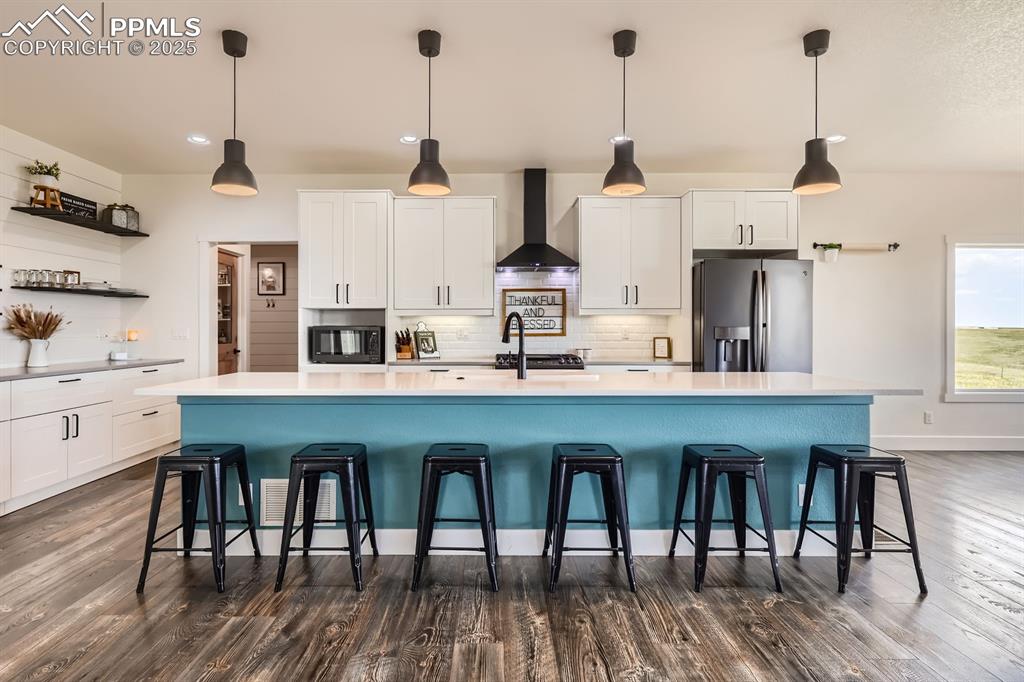 Image 11 of 29: Kitchen with white cabinets, stainless steel fridge with ice dispenser, a k