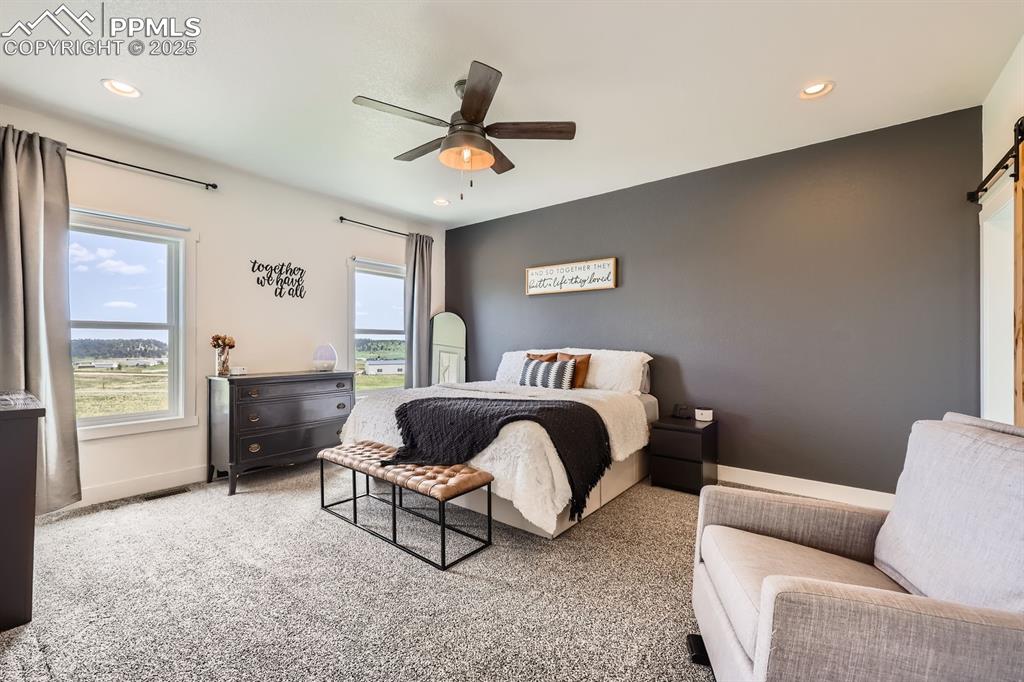 Image 13 of 29: Bedroom with recessed lighting, a barn door, carpet floors, and ceiling fan