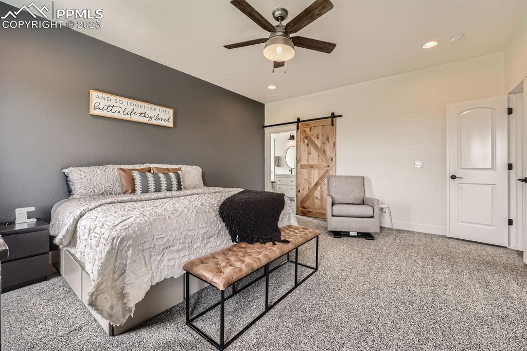 Image 14 of 29: Carpeted bedroom featuring a barn door, recessed lighting, and a ceiling fa