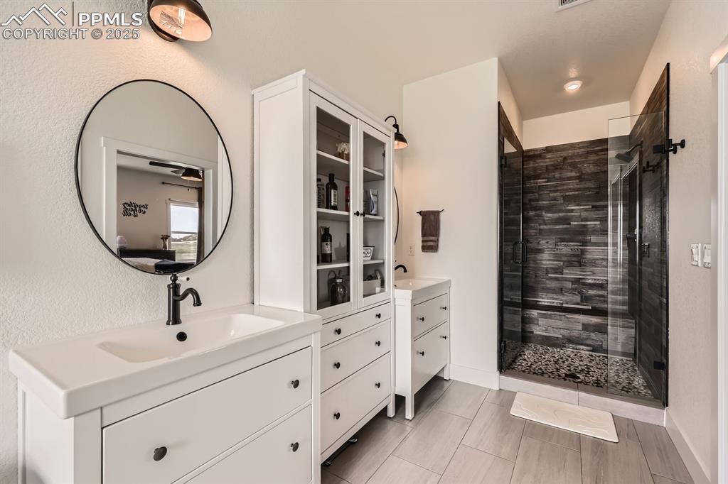 Image 15 of 29: Bathroom with two vanities and a stall shower