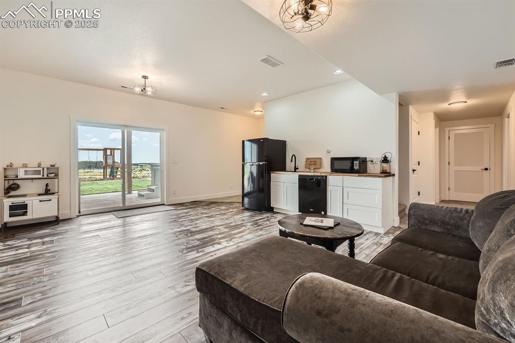 Image 18 of 29: Living area with bar with sink, light wood-style flooring, and recessed lig