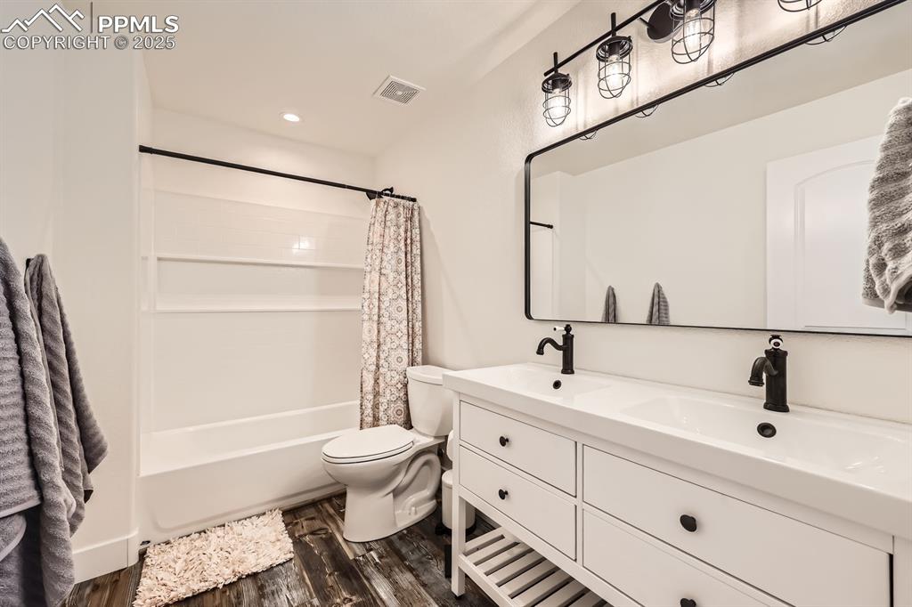 Image 20 of 29: Bathroom featuring double vanity, shower / bath combo with shower curtain,