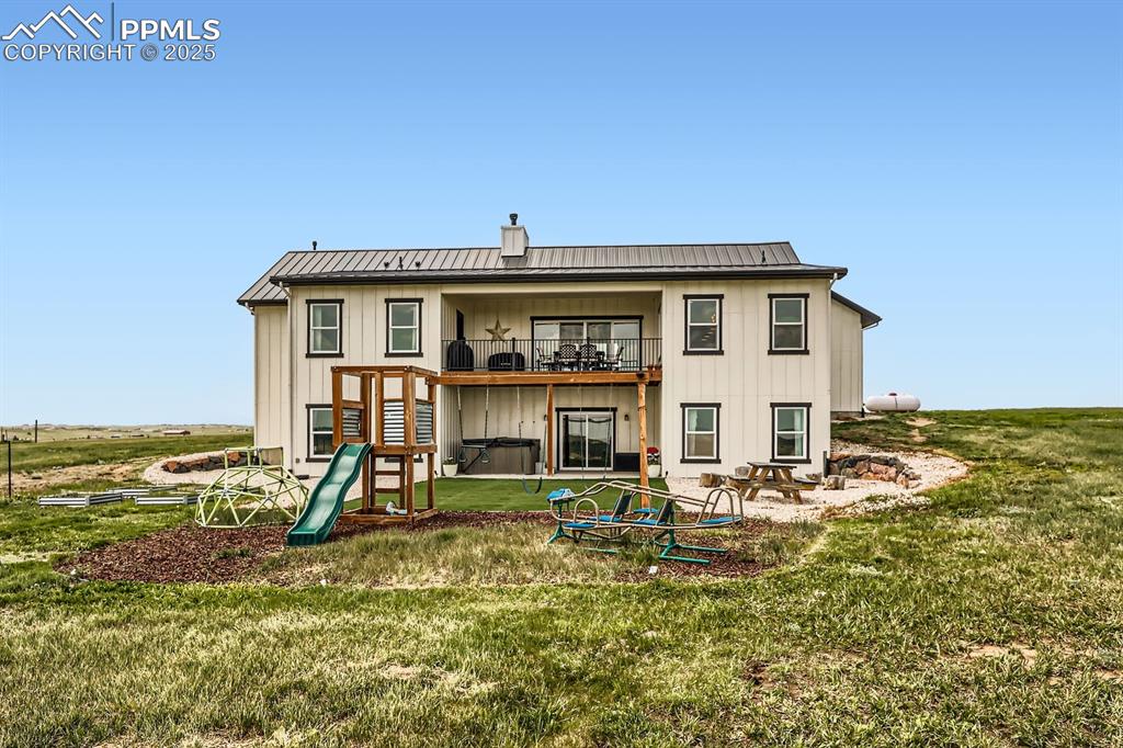 Image 28 of 29: Back of house featuring a lawn, board and batten siding, and a metal roof