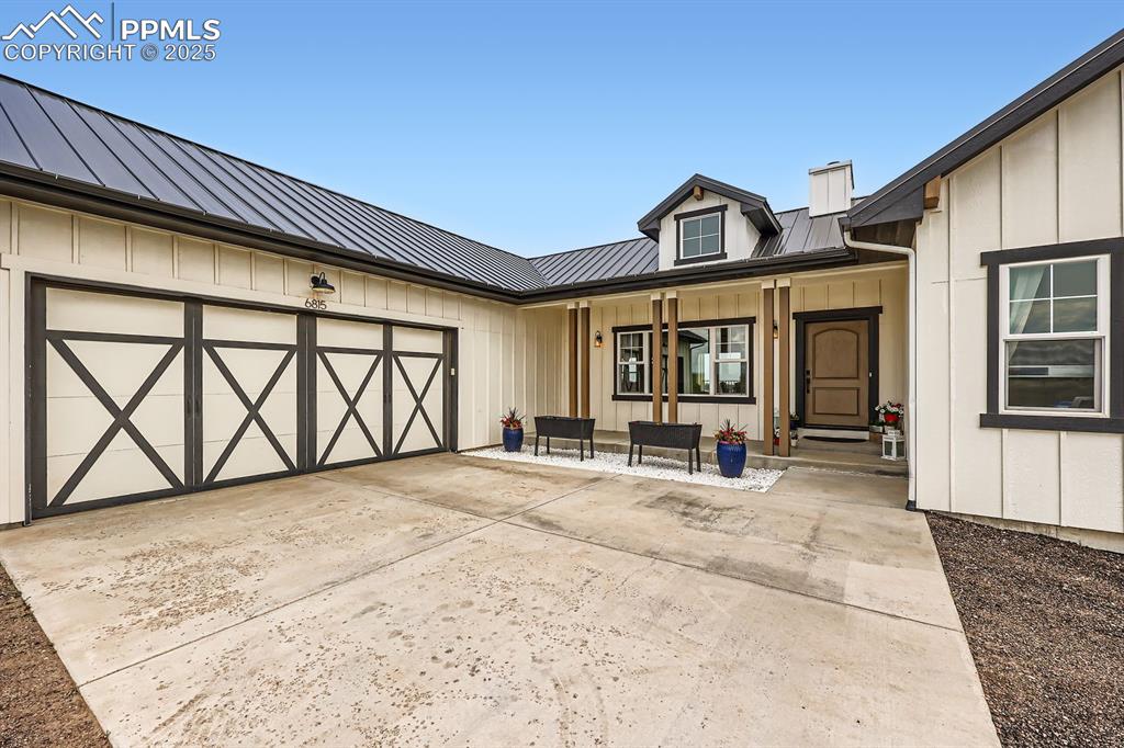 Image 4 of 29: Doorway to property with board and batten siding, a porch, a metal roof, an