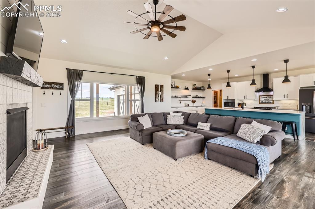 Image 5 of 29: Living room featuring a fireplace with raised hearth, vaulted ceiling, rece