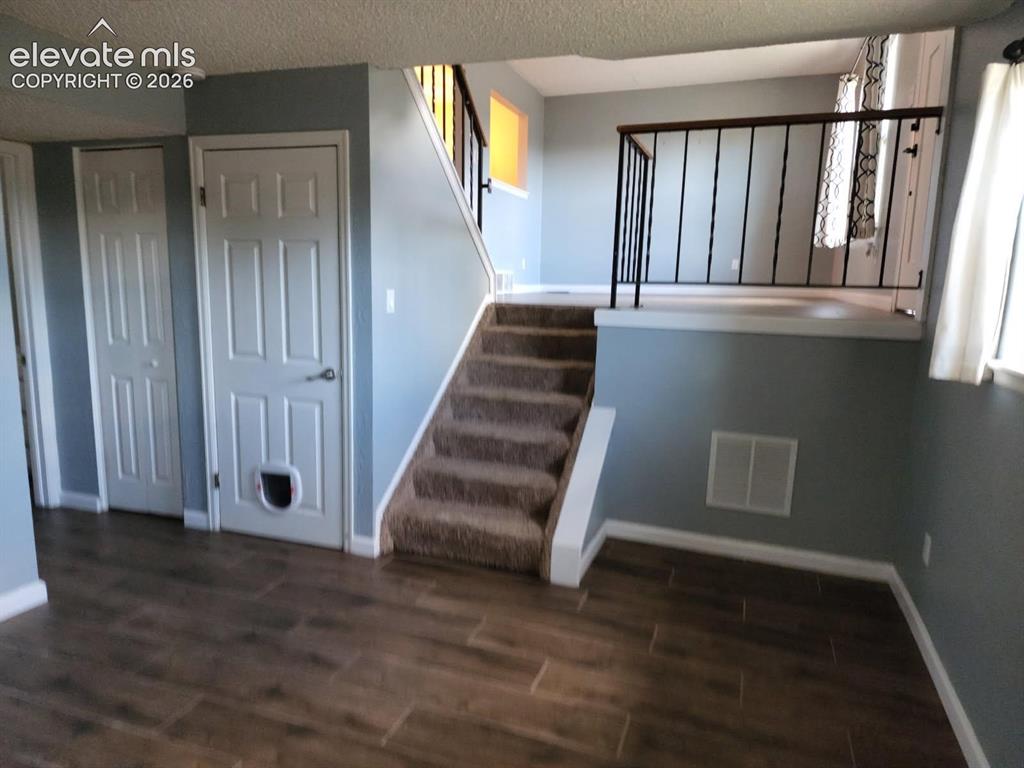 Image 10 of 12: Split-level interior featuring wood-finish flooring, carpeted stairs, and a