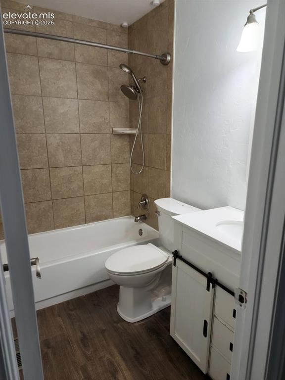 Image 4 of 12: Bathroom featuring a white vanity with sliding barn door hardware, an integ