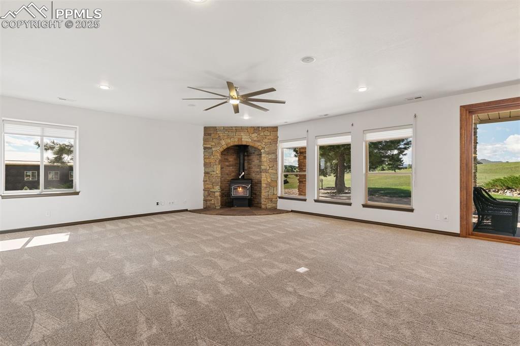Image 38 of 50: Basement rec room with wood burning stove