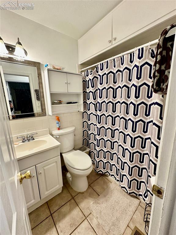 Image 15 of 20: Full bathroom featuring tile walls, tile patterned floors, vanity, toilet, 