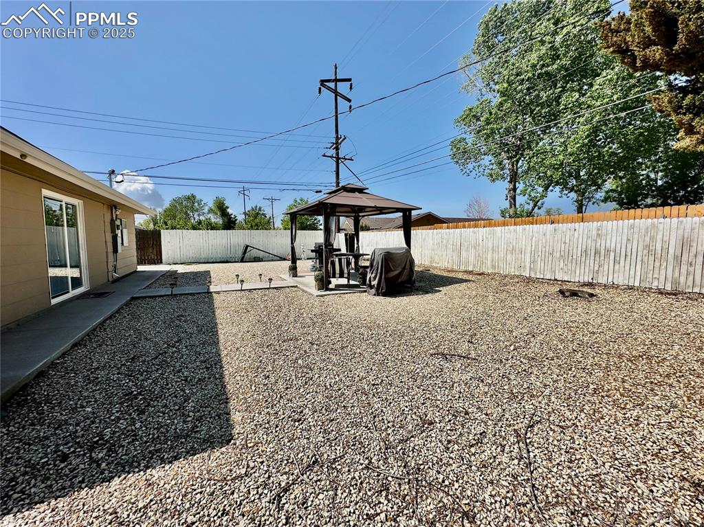 Image 19 of 20: Fenced backyard with a gazebo and a patio
