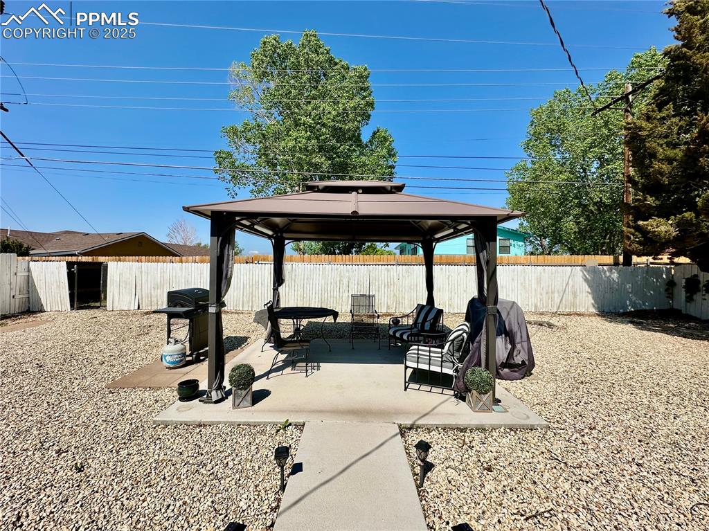 Image 20 of 20: View of patio with a gazebo, a fenced backyard, and area for grilling