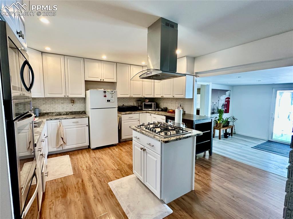 Image 5 of 20: Kitchen featuring stainless steel appliances, island range hood, decorative