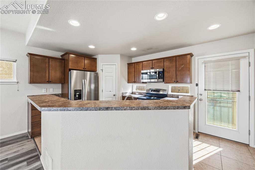 Image 10 of 30: The well-appointed Kitchen features a tile floor, pantry, wood cabinetry, a