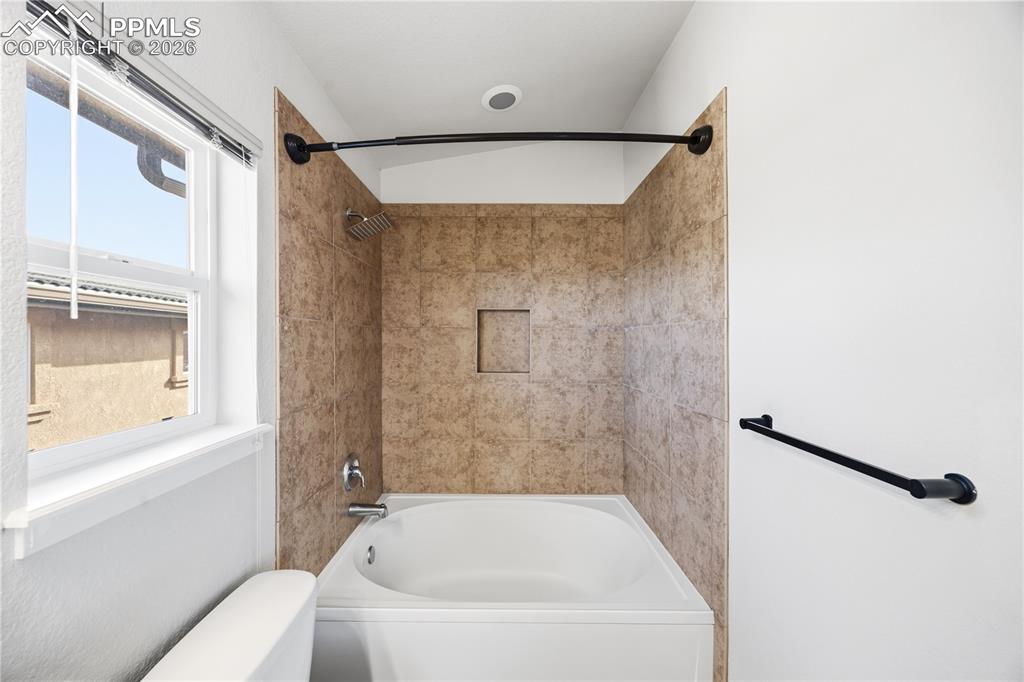 Image 25 of 30: Tiled tub/shower in the Primary Bathroom.