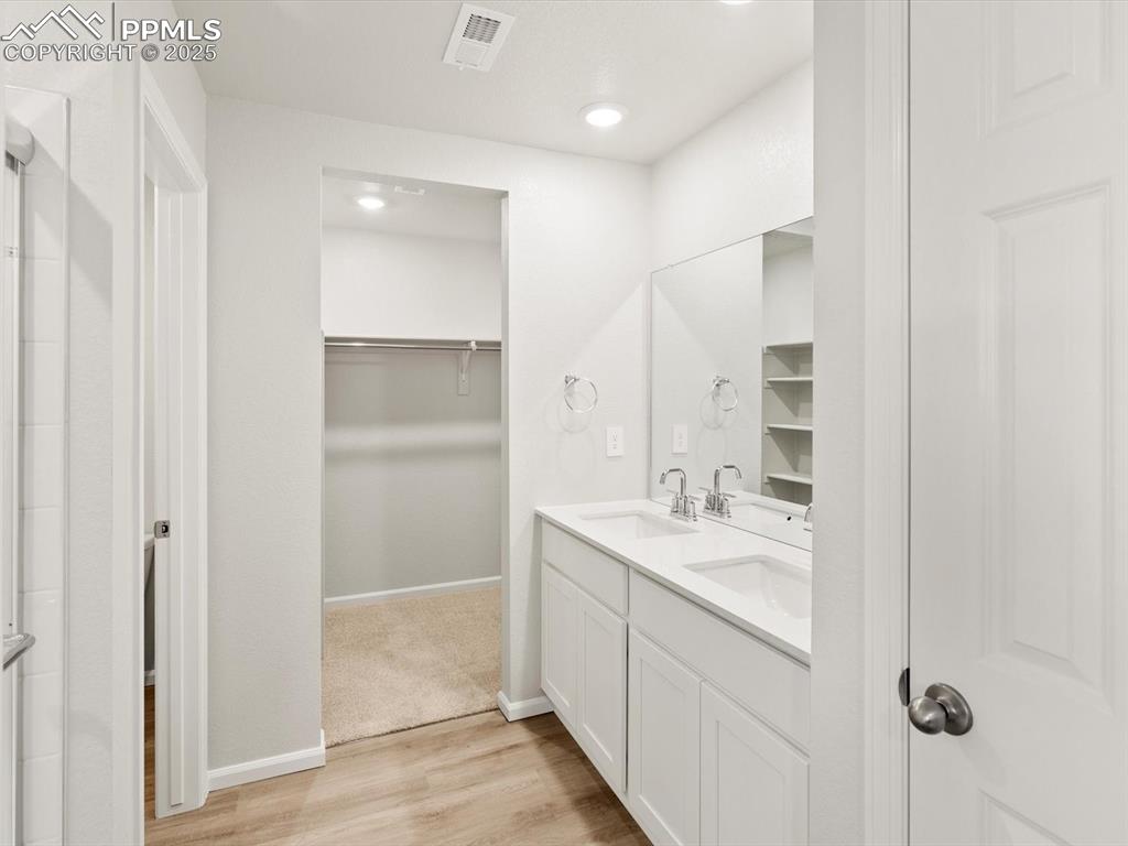 Image 20 of 23: Bathroom featuring light wood-type flooring, a walk in closet, double vanit