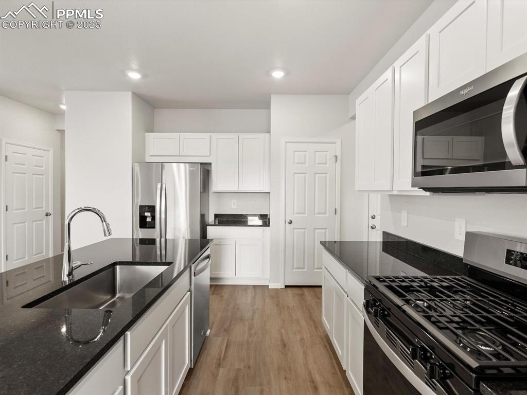 Image 5 of 23: Kitchen featuring appliances with stainless steel finishes, white cabinets,