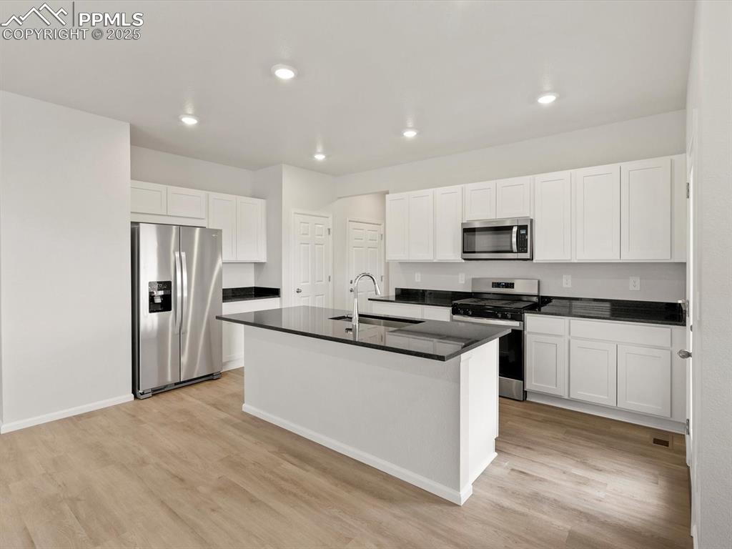 Image 6 of 23: Kitchen featuring appliances with stainless steel finishes, white cabinets,