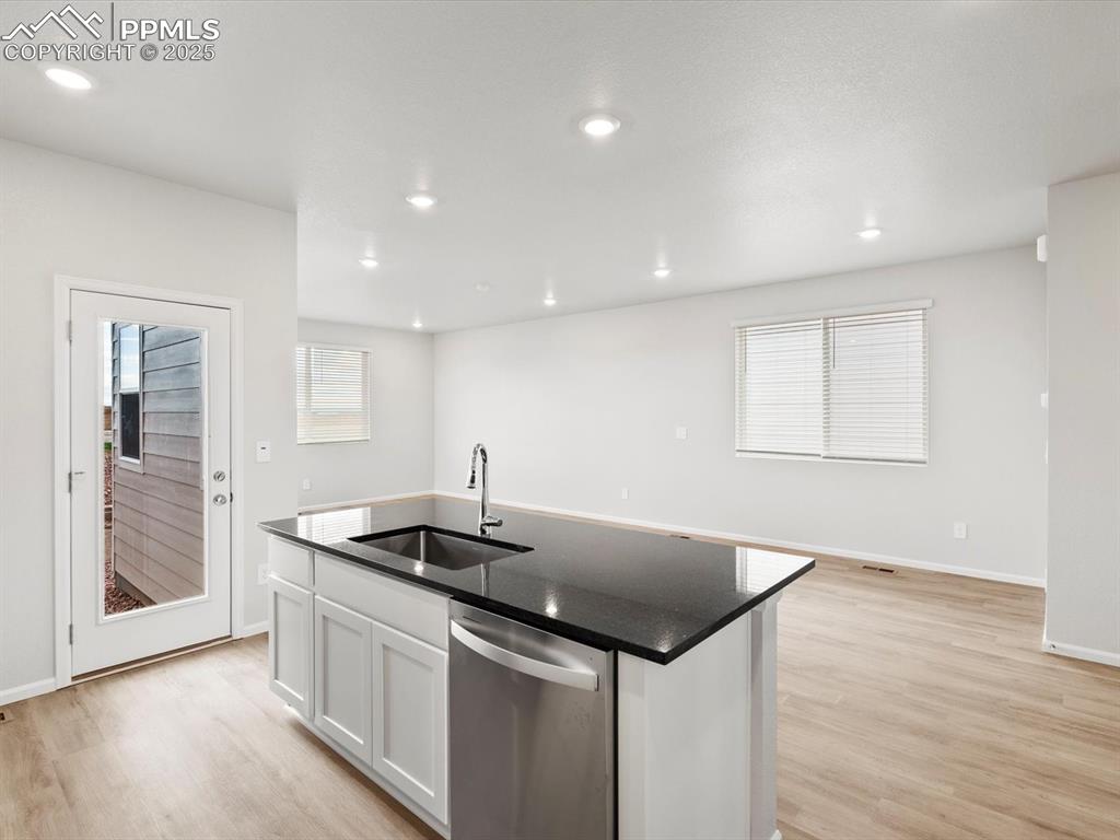 Image 7 of 23: Kitchen with stainless steel dishwasher, white cabinets, light wood-type fl