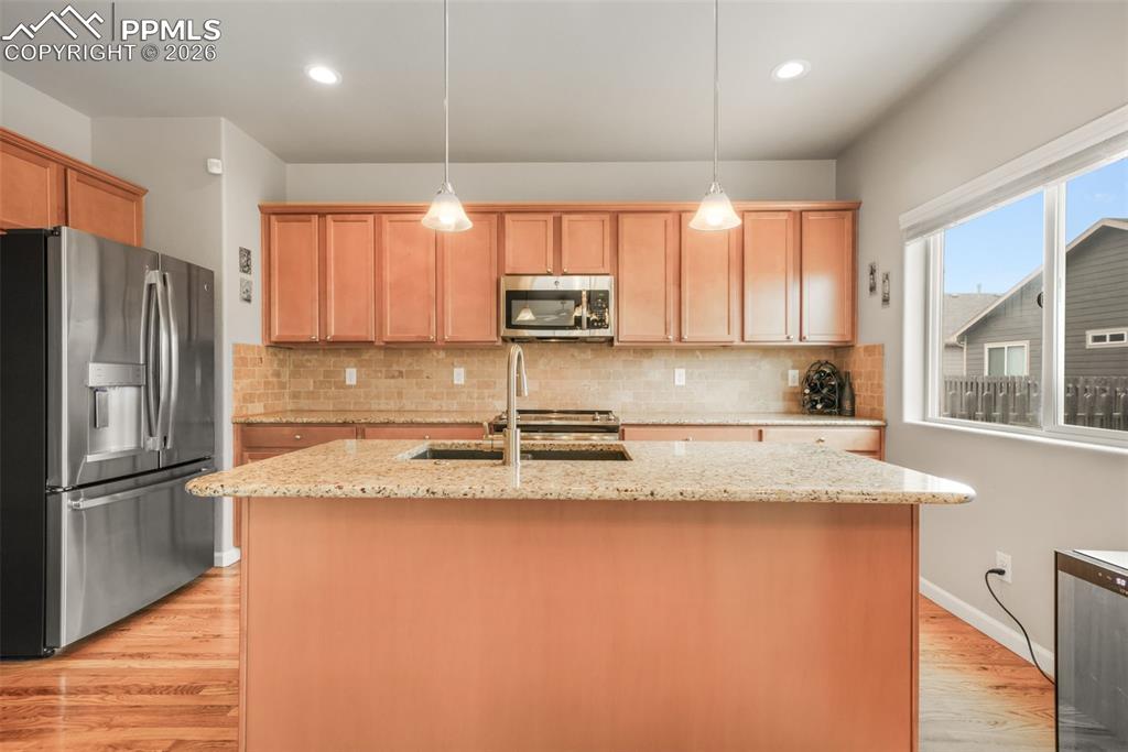 Image 13 of 50: Open-concept living space with wood-finish flooring, walk-out glass patio d