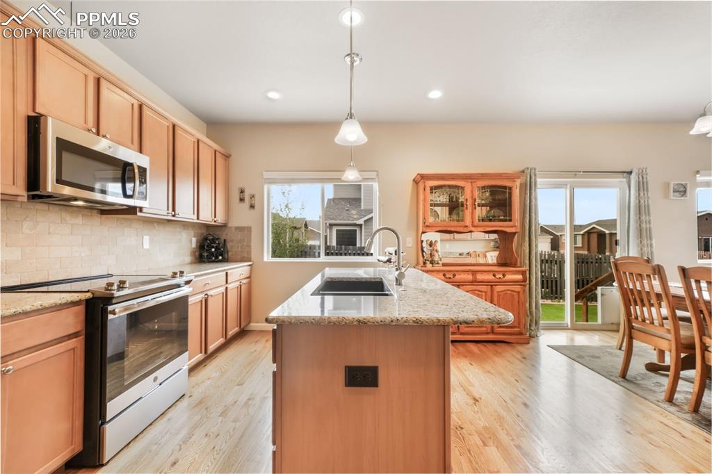 Image 16 of 50: Kitchen featuring wood-finish flooring, a central island with a granite cou
