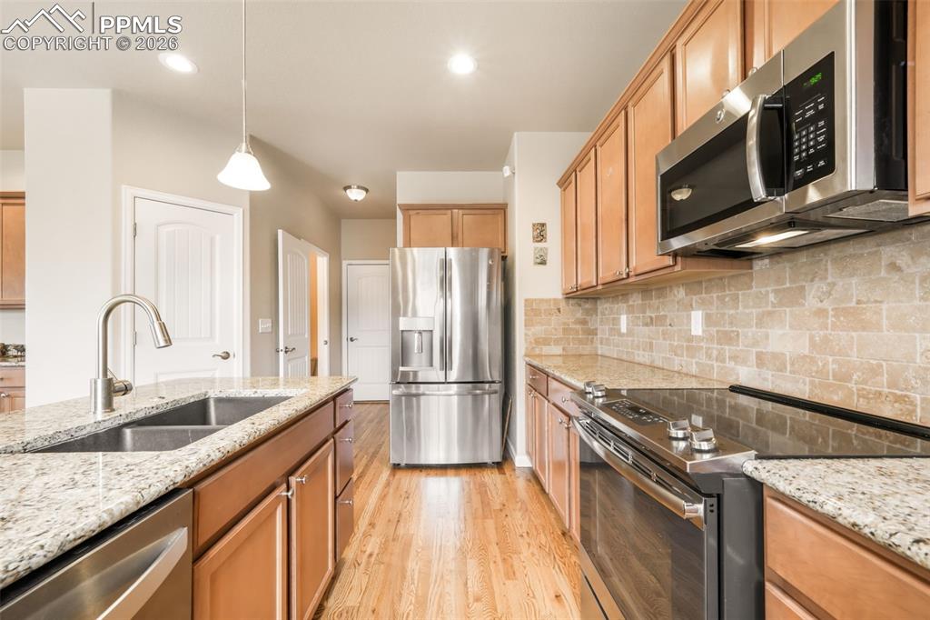 Image 18 of 50: Kitchen island with granite countertop, undermount sink, and stainless stee