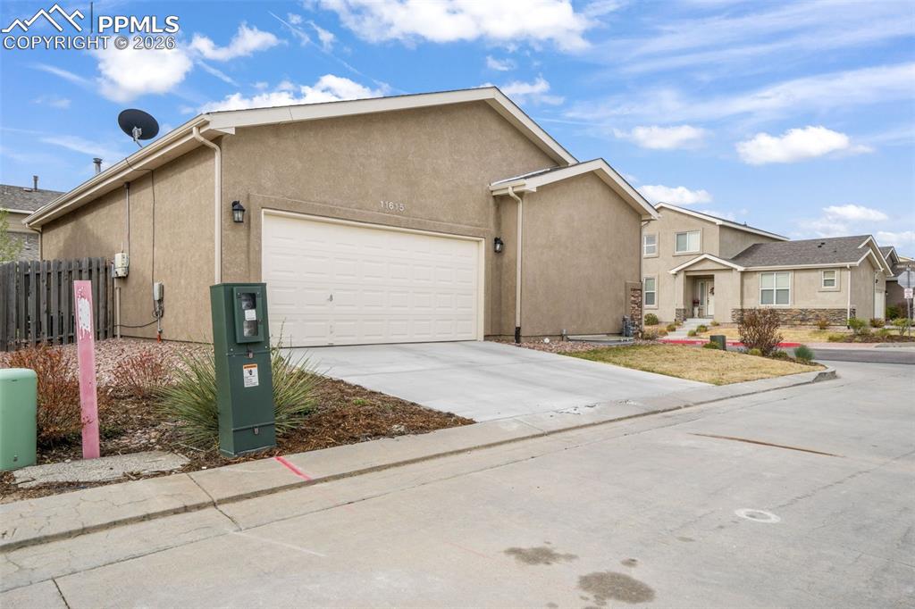 Image 2 of 50: Stucco exterior featuring a two-car garage, concrete driveway, and front po