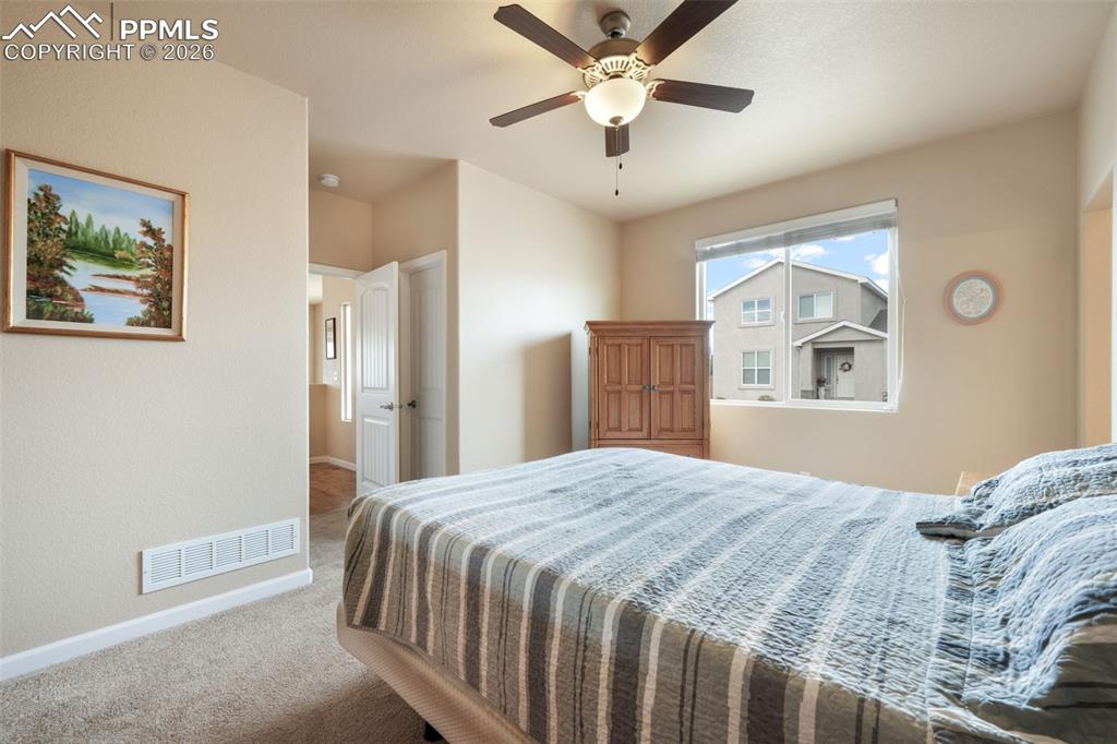 Image 26 of 50: Carpeted bedroom featuring a ceiling fan with integrated lighting, a large 