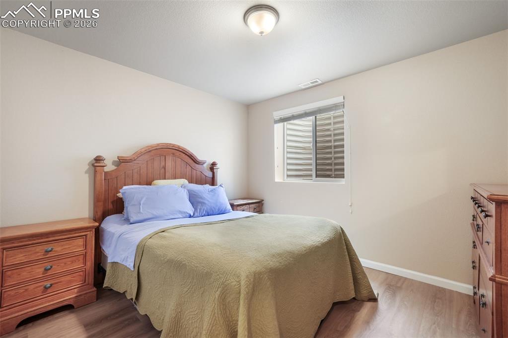 Image 35 of 50: Bedroom featuring wood-finish flooring, neutral wall tones, white trim, and